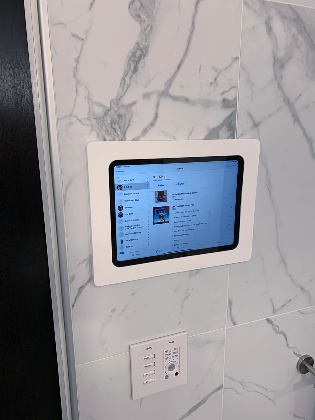 Photo of a wall with a tablet mounted, located in a master bathroom